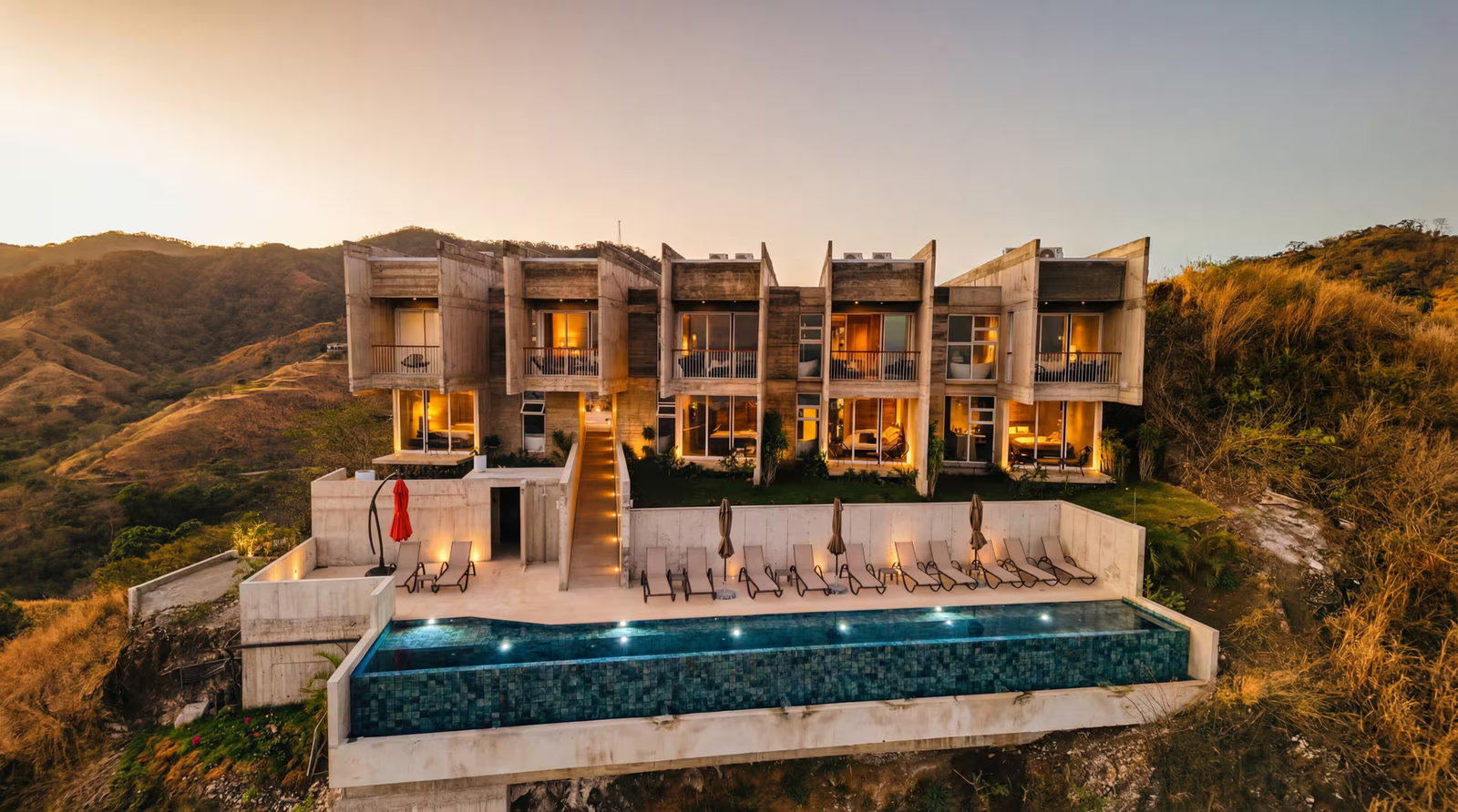 Vista Pacifico at golden hour: five board-formed concrete guest suites stepping down a Guanacaste hillside above a lit infinity pool.